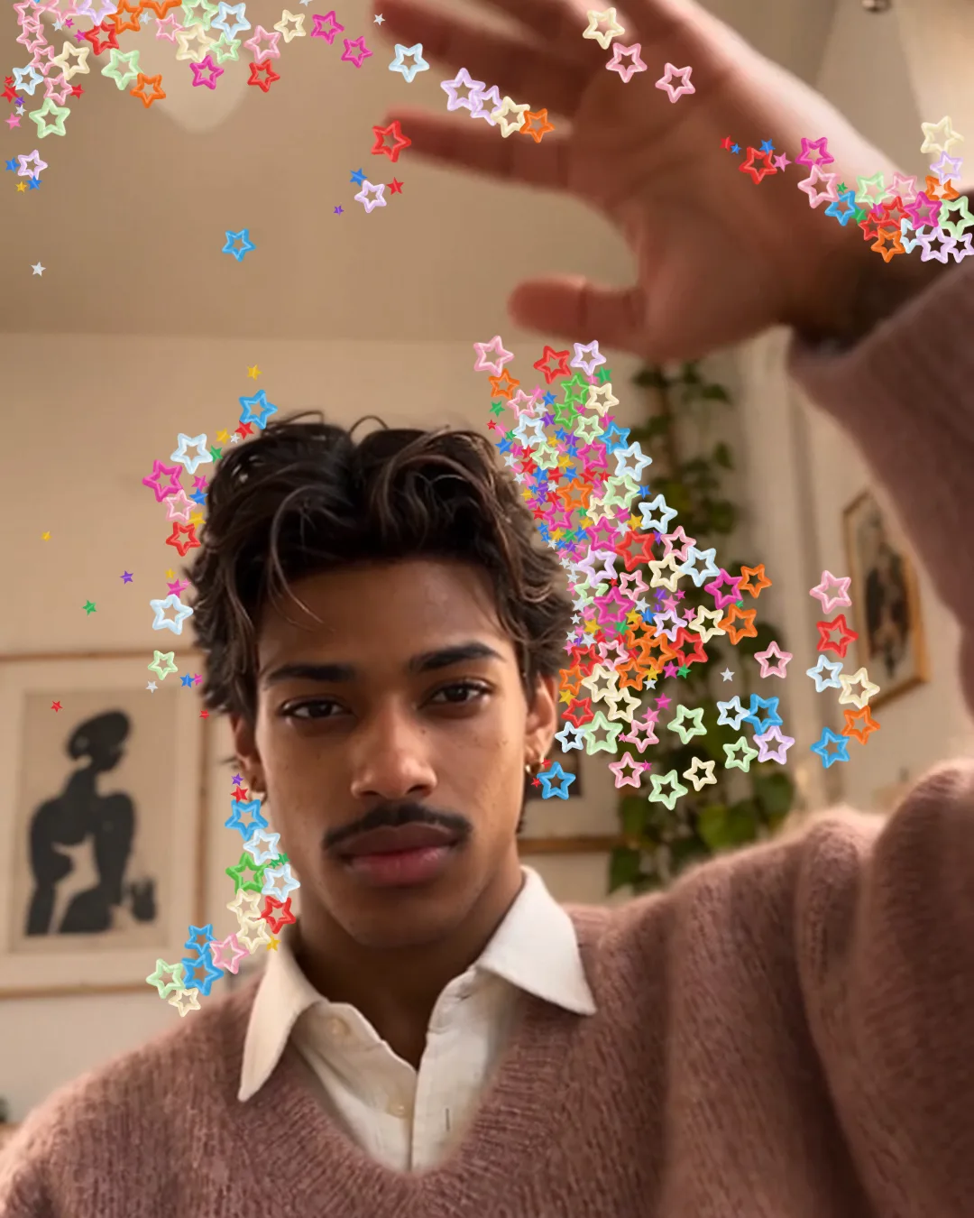 Colourful stars clinging around a man’s raised hands and the side of his head